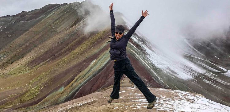 A woman jumping on top of a mountain