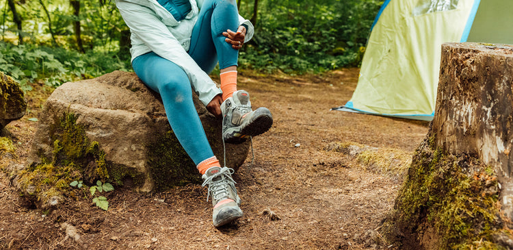 a woman removes her hiking shoe at camp