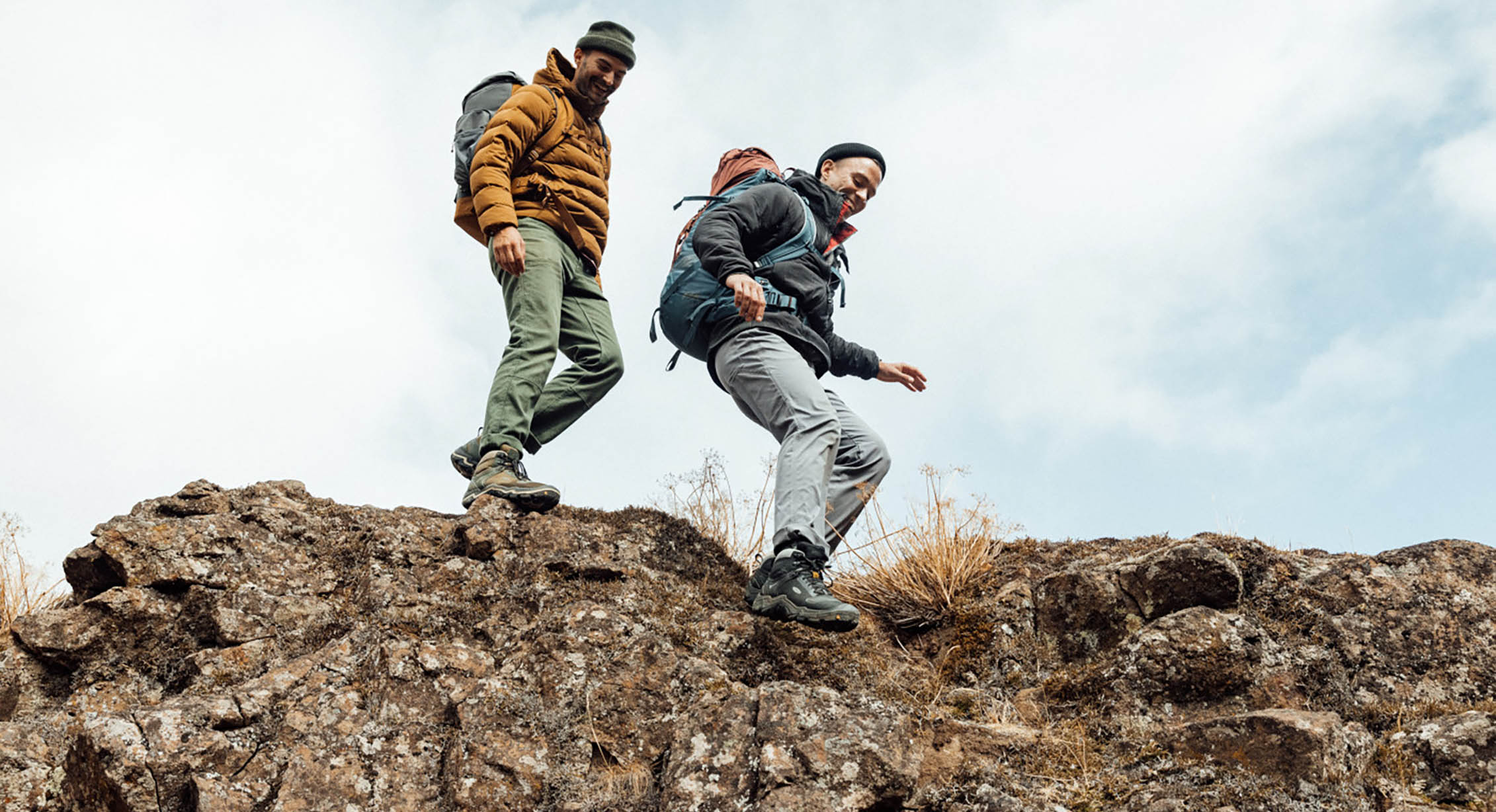 two hikers happily hike down a rocky slope