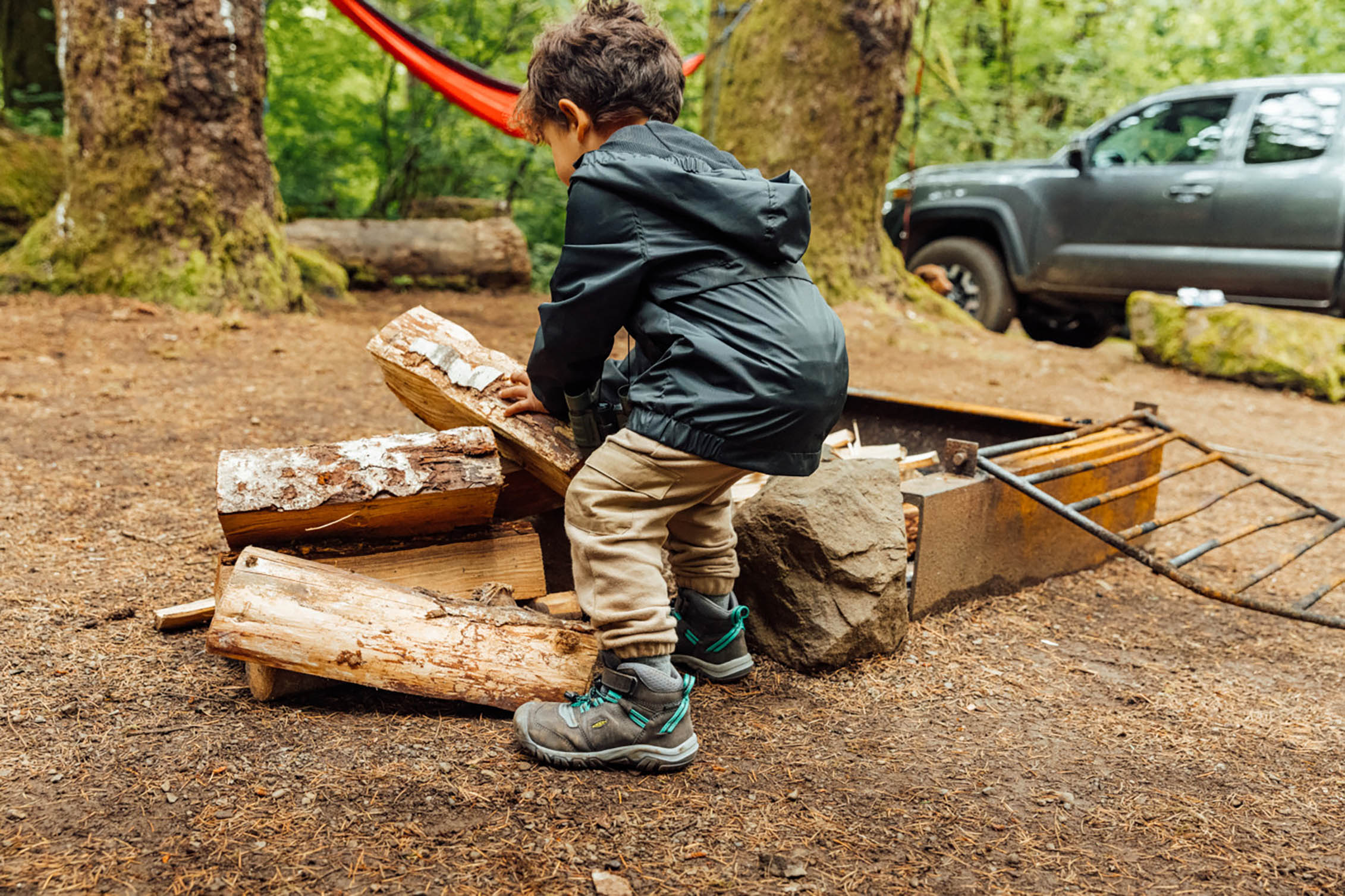 A toddler carrying logs