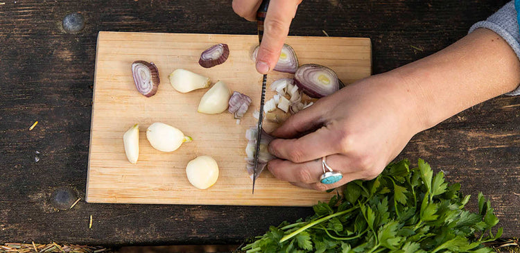 A person chopping vegetables at a campsite