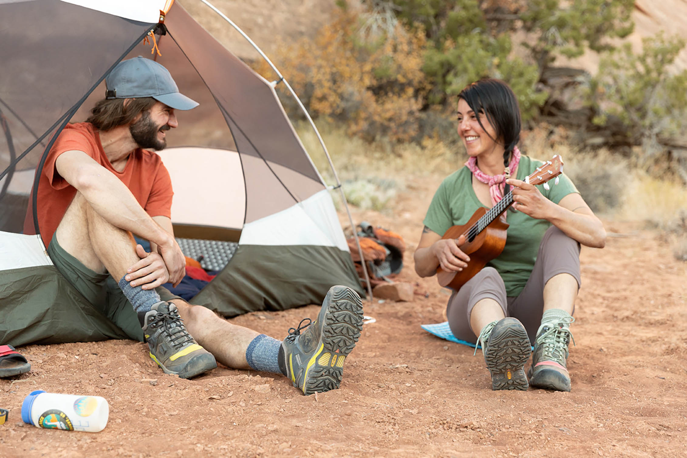 Playing a ukulele outside a tent while camping