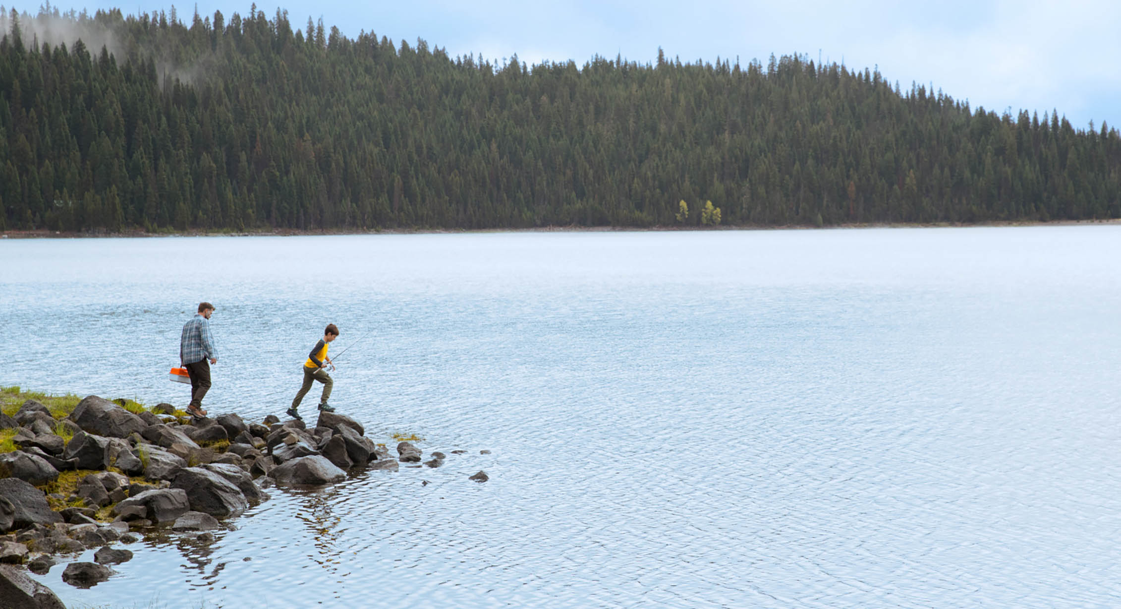 a father a son fishing on the edge of a lake