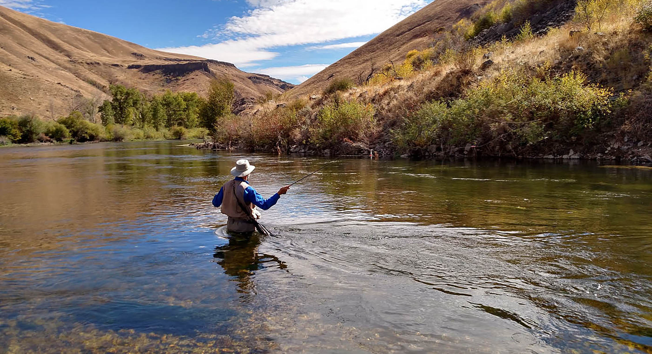 a person fishes from the middle of a river