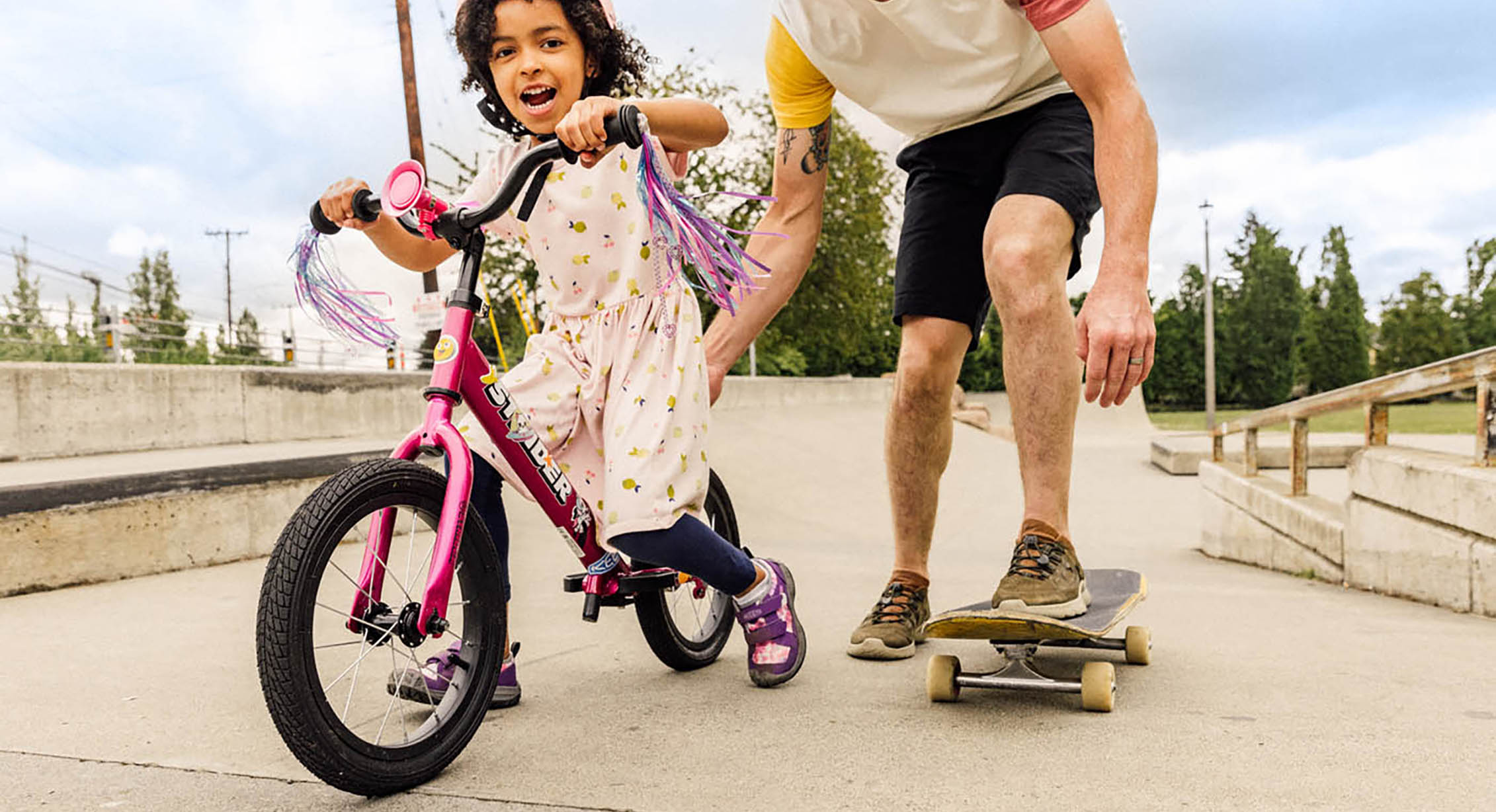 child riding a bike while dad skateboards