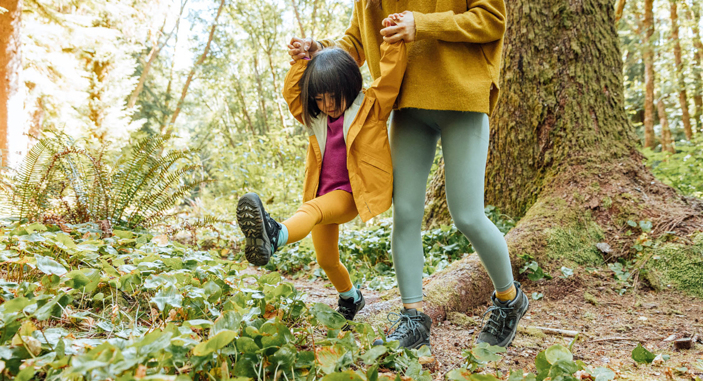 a kid and their parent play in the forest