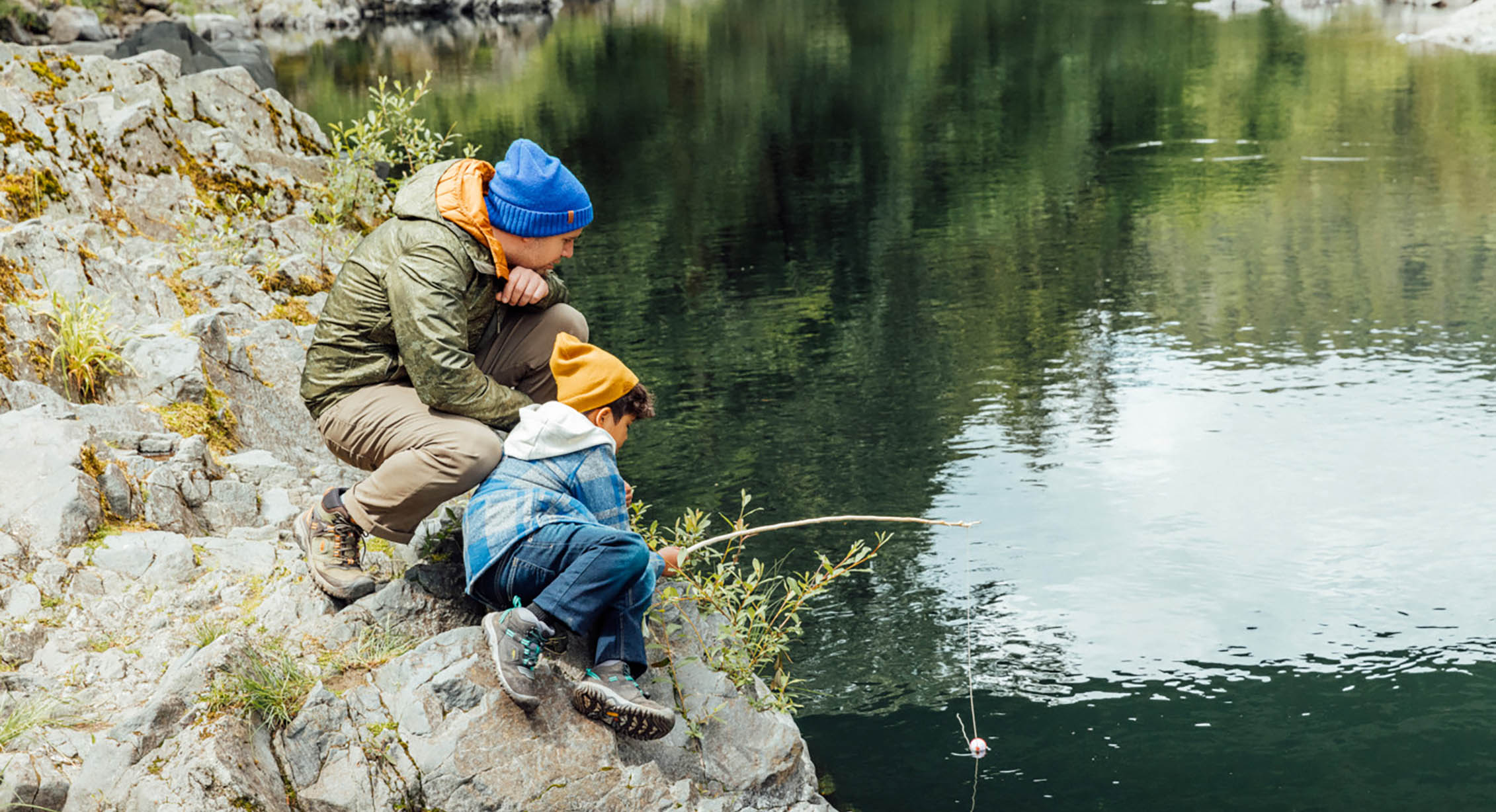 a father and child fishing along a river