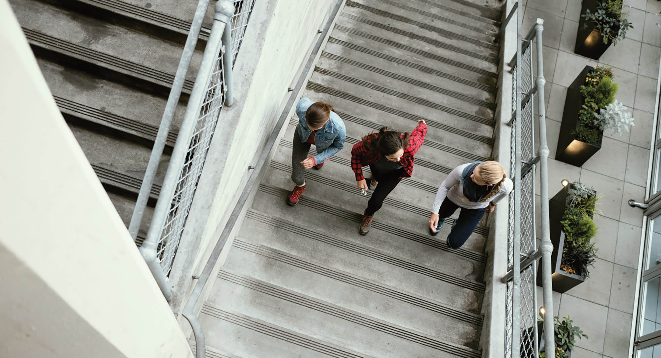 three people run up a set up concrete stairs