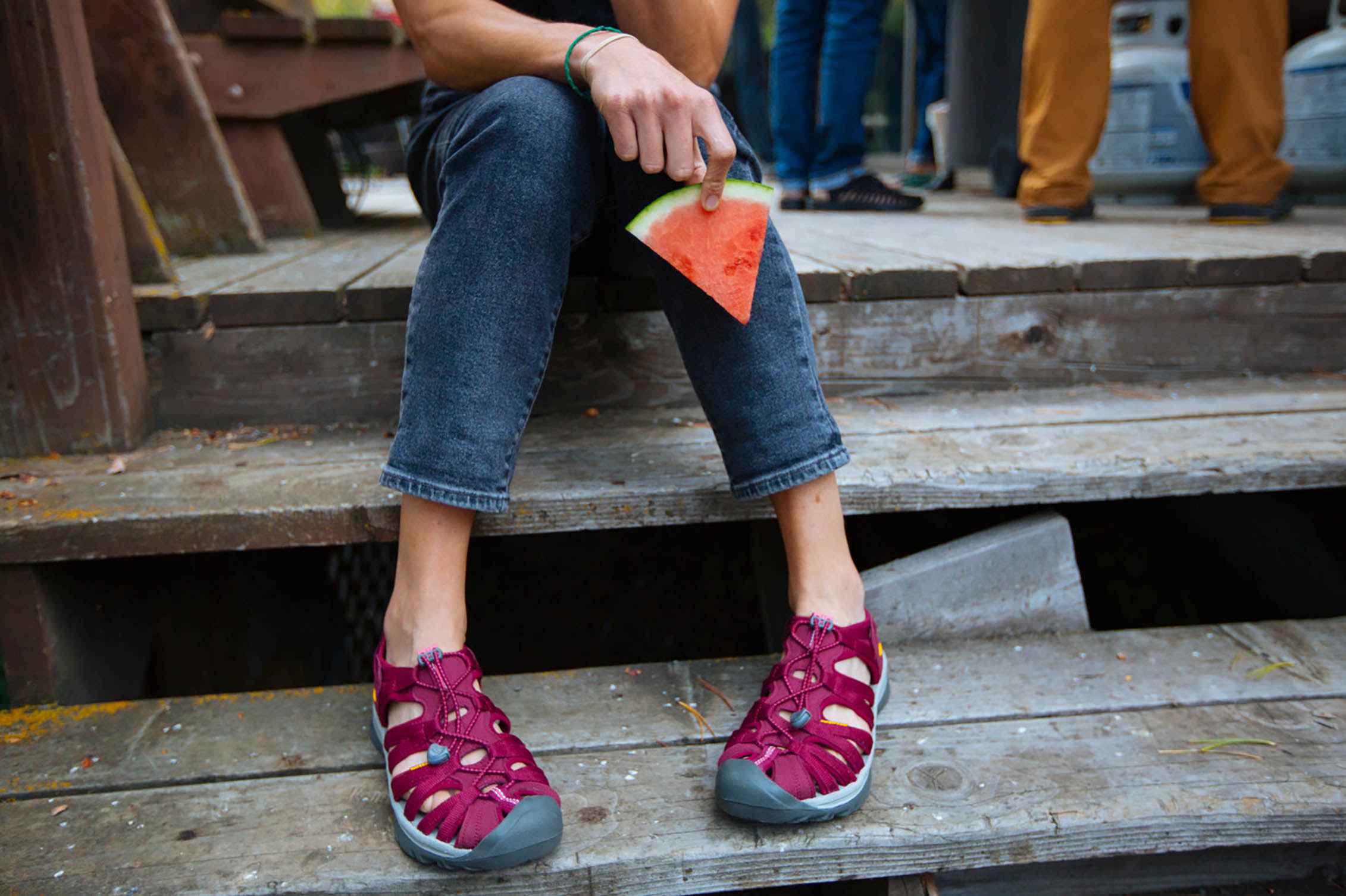 A woman sitting with a slice of watermelon