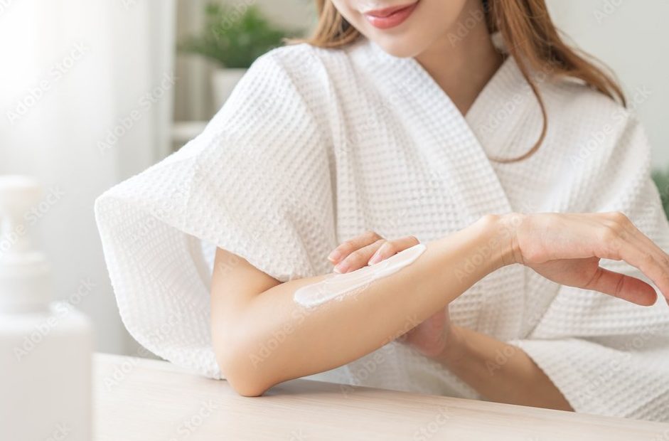 A woman applying shea butter lotion to her skin